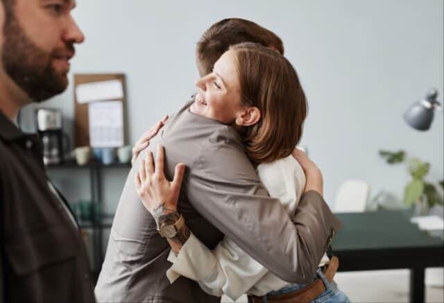 Colleagues hugging in the office - man and woman showing genuine connection