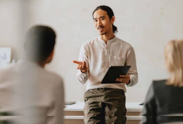 Communication workshop: Man in white linen shirt leads conversation with other participants