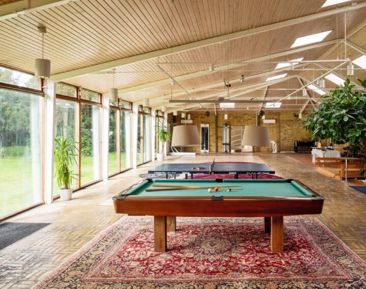 Sunnanå course venue: Large room with gym, pool table and table tennis, large windows along one wall and garden outside