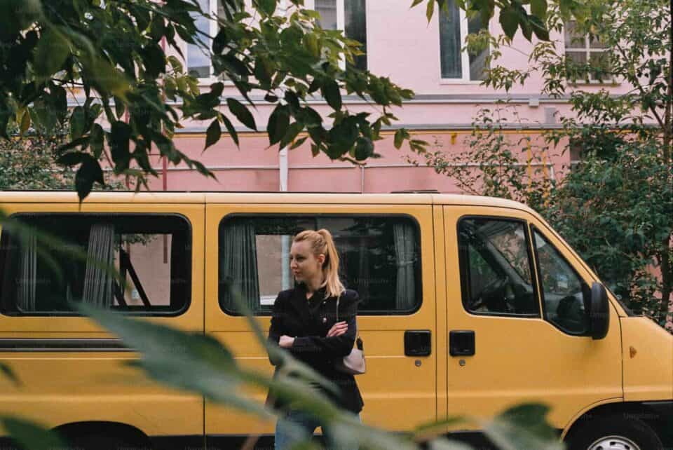 Blonde woman in front of yellow car in creative urban environment
